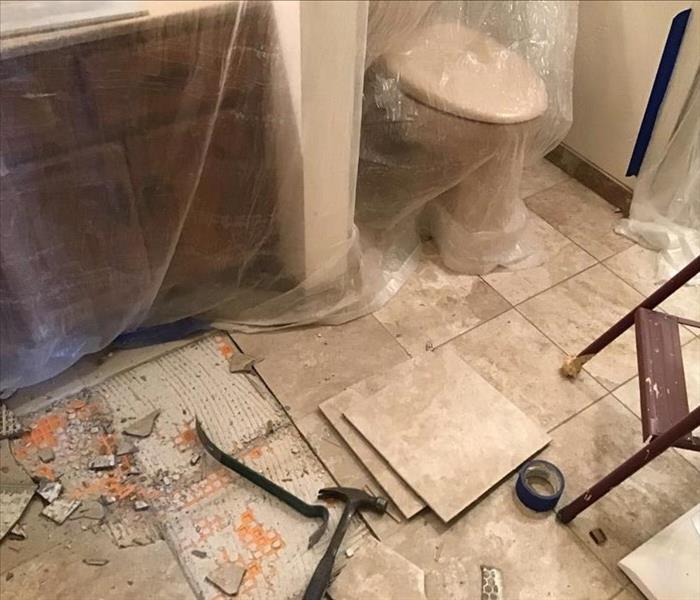 a bathroom and tiled floor being demoed due to a water damage