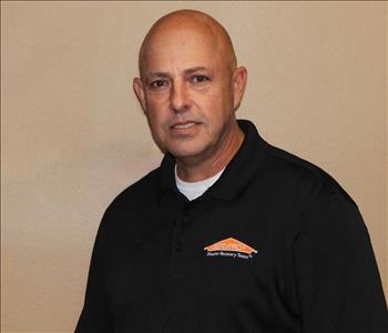 A SERVPRO Employee standing in front os a tan background
